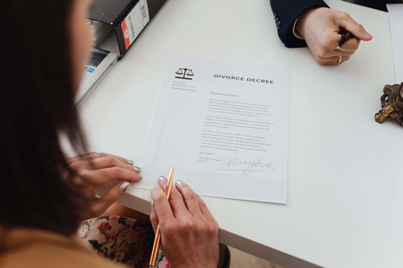 services-01 A close-up shot of two people signing a divorce decree at a law office table.